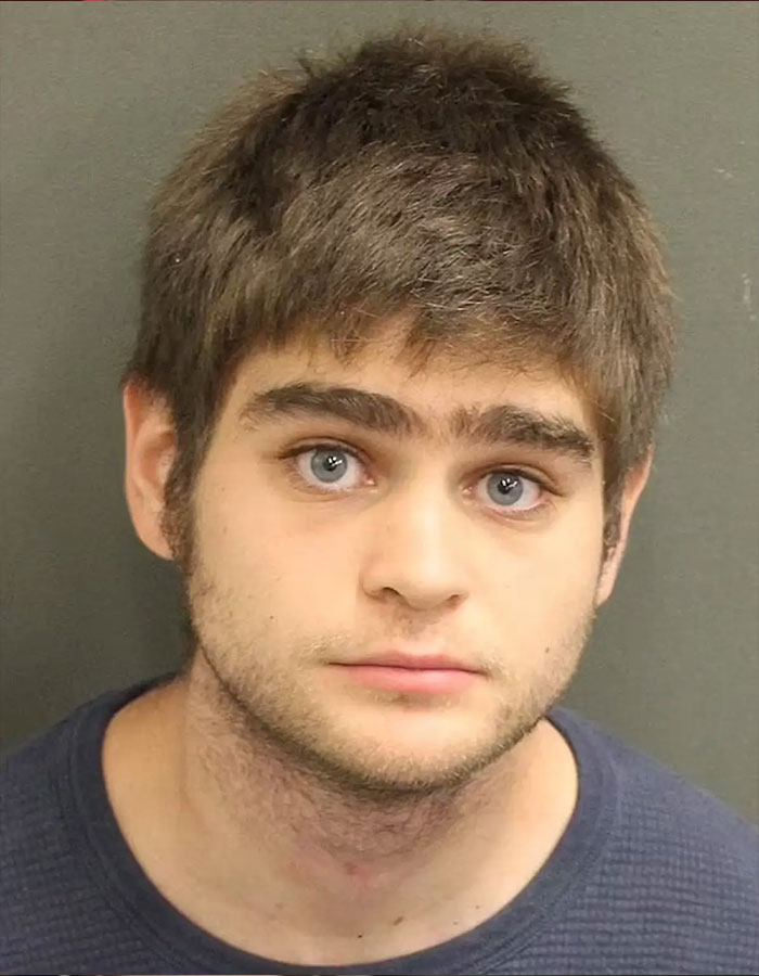 Young man with short brown hair and blue eyes in a mugshot related to violent Disney World incident twist.