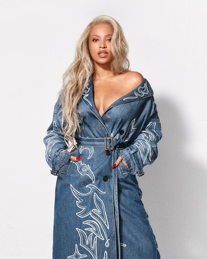Beyoncé wearing a blue denim coat with white embroidery, posing against a plain white wall for a denim ad campaign. - 8