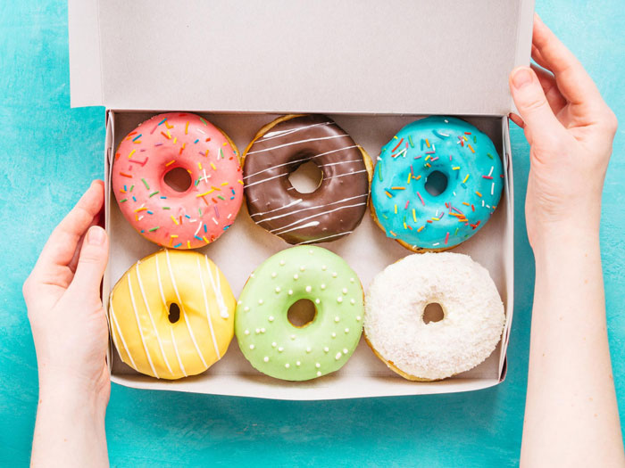 Box of colorful donuts held by hands, representing the revenge served instead of donuts in a parking spot dispute.