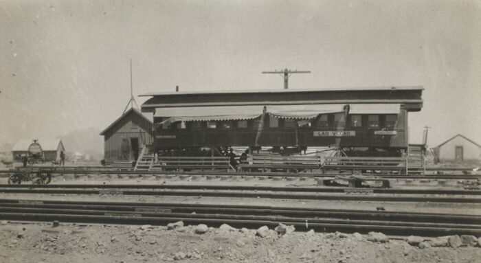 Historic train car and small buildings along railroad tracks during the birth of Vegas in early 1900s desert landscape.