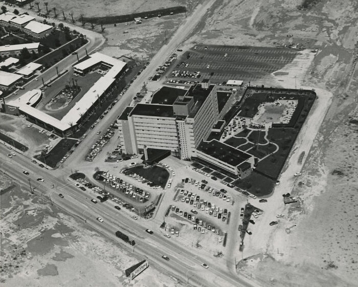 Aerial view of historic Las Vegas casino and surrounding desert landscape showing early city development and parking lots.