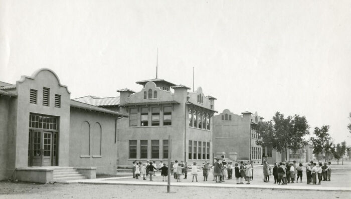 Historic black and white image of early Vegas schoolchildren playing outside a building during the birth of Vegas era.