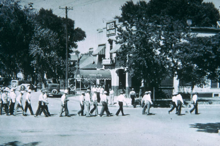 Group of men crossing street near historic Hotel National in early Vegas, showcasing the birth of Vegas in a 1900s street scene.