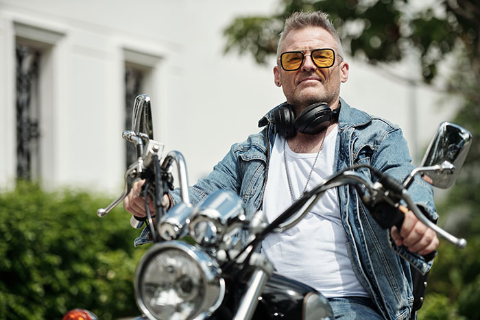 Man in yellow sunglasses and denim jacket on motorcycle, symbolizing neighbors fight over driveway dispute.