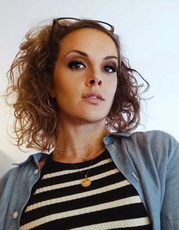 Young woman with curly hair wearing striped top and denim shirt, representing rare disorder pain dismissed by doctors for years. Young woman with curly hair wearing striped top and denim shirt, representing rare disorder pain dismissed by doctors for years.