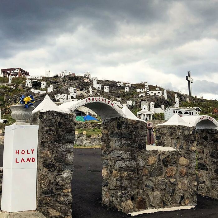 Abandoned Holy Land site with stone arches and numerous small white buildings under cloudy skies.