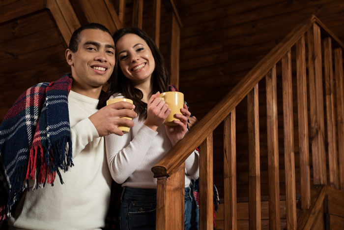 Couple smiling inside a wooden house, holding mugs, illustrating a lady dealing with a shameless ex taking over her home. Couple smiling inside a wooden house, holding mugs, illustrating a lady dealing with a shameless ex taking over her home.