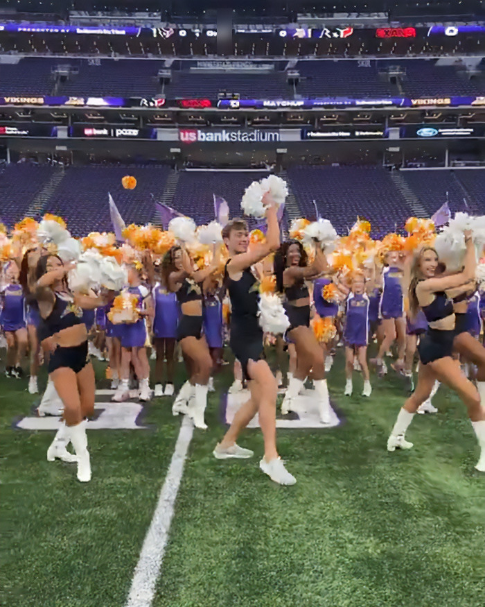 Male cheerleaders performing with female cheerleaders on football field, highlighting men infiltrating women's spaces debate.