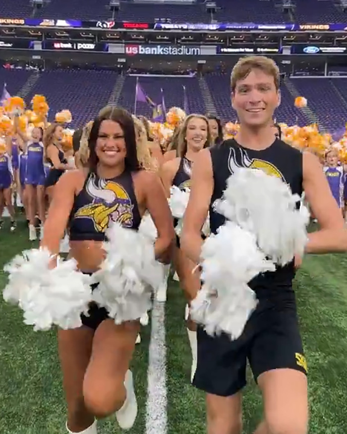 Male and female cheerleaders performing together on an American football field during a game.