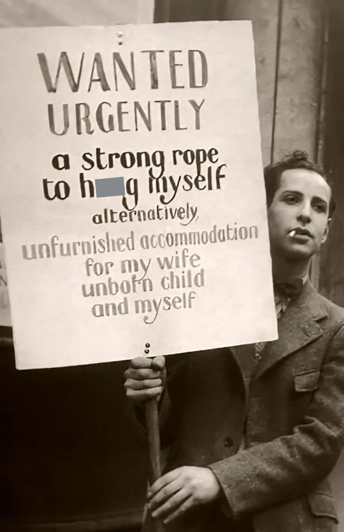 Black and white historical photo of a man holding a humorous protest sign in a vintage setting from weird historical photos.