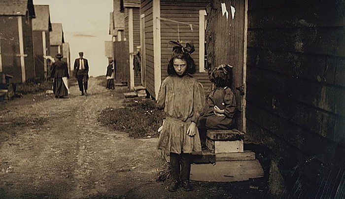 Sepia-toned historical photo of a young girl with dolls on a dirt street, capturing a wild moment in history.
