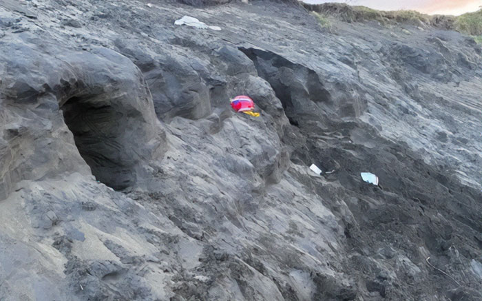 Rocky sandy area with small caves where a dad tragically lost life after being buried alive while digging sand with kids.