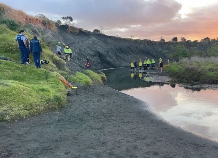 Rescue team at a sandy riverbank at sunset after a dad lost his life being buried alive while digging sand with kids.