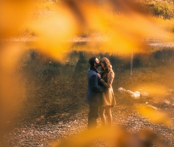 Couple embracing near a riverbank in autumn, representing love and commitment in a fiance non biological child wedding setting.