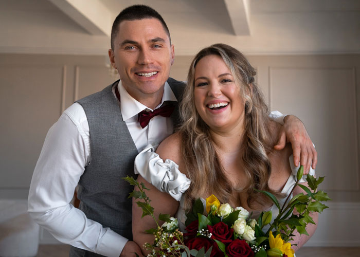 Happy couple smiling with bouquet as fiance and sister prepare to invite guests to wedding celebration indoors.