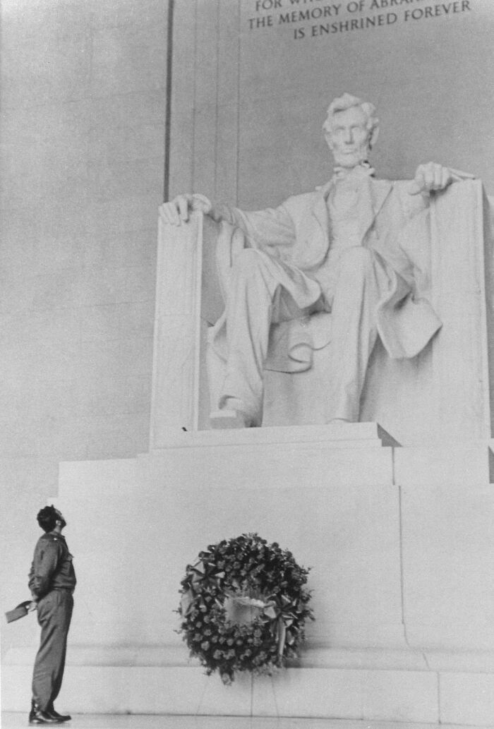 Man standing before the Lincoln Memorial statue with a floral wreath, capturing iconic moments in history.
