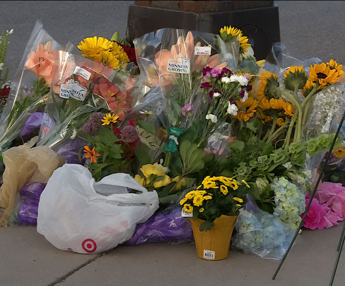 Floral memorial with sunflowers and mixed bouquets placed in tribute related to Minneapolis massacre culprit incident.