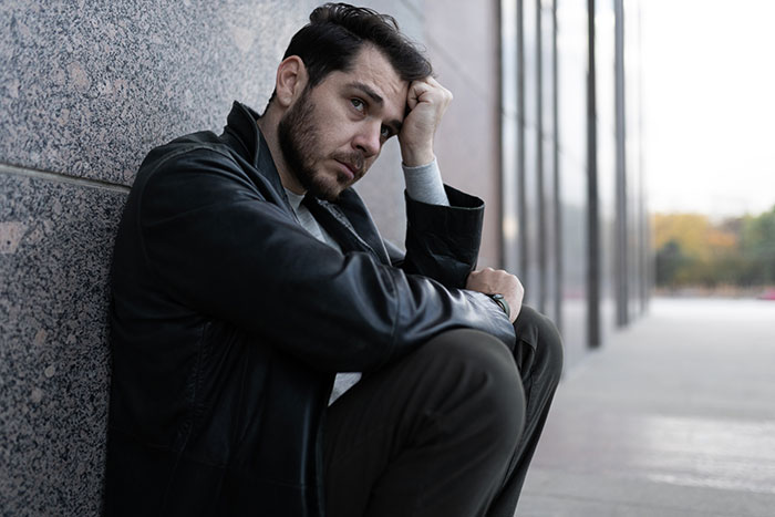 Man sitting alone outside a building, appearing thoughtful and concerned, reflecting on life in prison experiences.