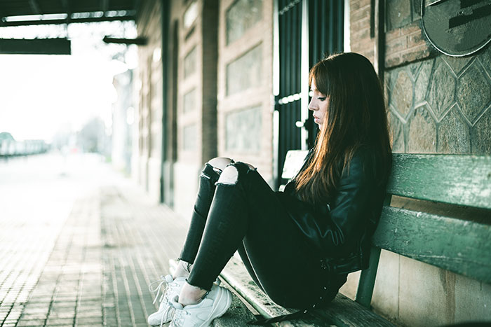 Young woman sitting alone on a bench, reflecting on life in prison and the challenges inmates face daily.