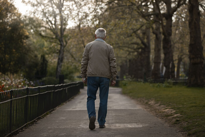 Elderly man walking alone on a quiet path in a park, evoking a sense of terrifying things people swear they've seen.