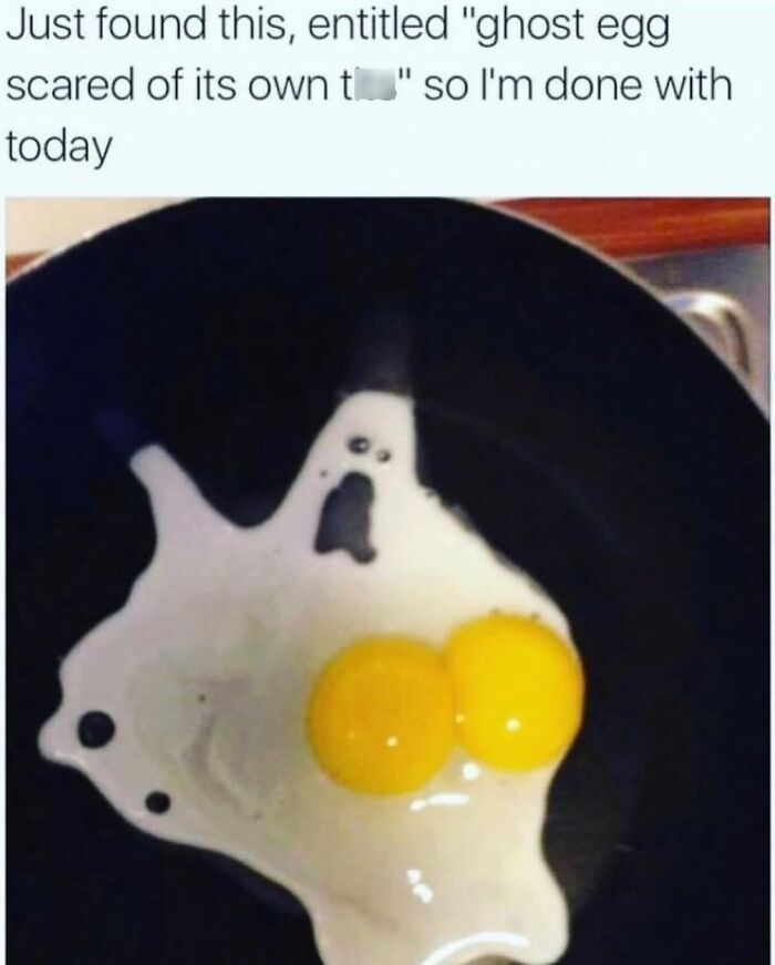 Fried egg shaped like a ghost with two yolks in a black pan, humorously captioned about a spooky egg meme.