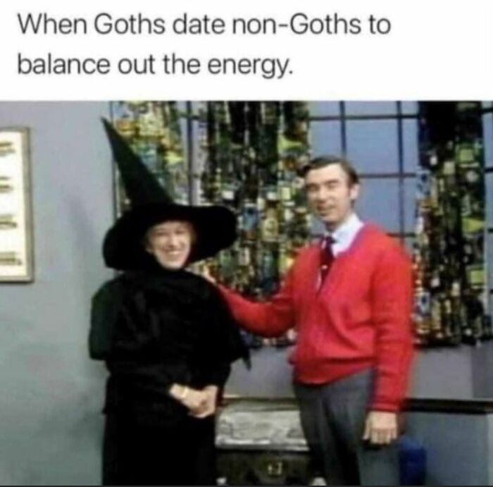 A goth dressed as a witch standing next to a man in a red sweater, humorous meme about dating energy balance.