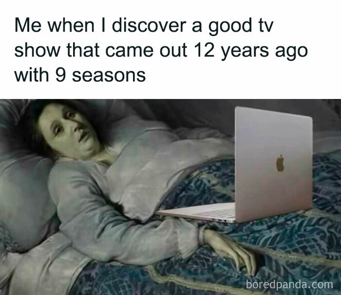 Person lying in bed looking exhausted with laptop, illustrating feeling after discovering a long TV show - hilarious memes theme.
