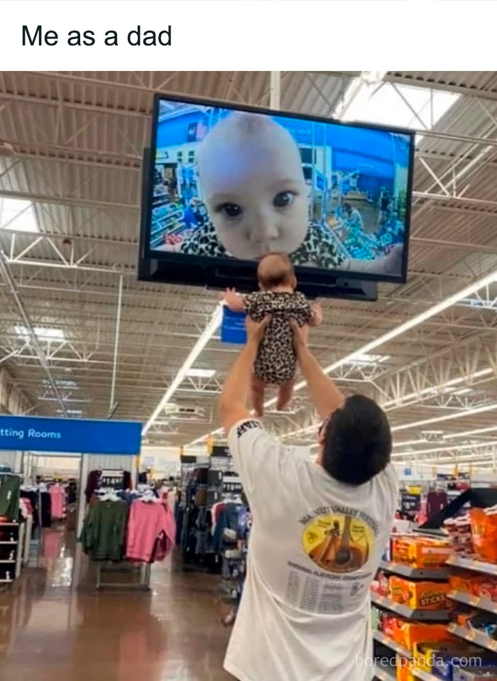 Man holding baby in front of a store TV showing baby's face, funny entertaining post to fight boredom with memes.