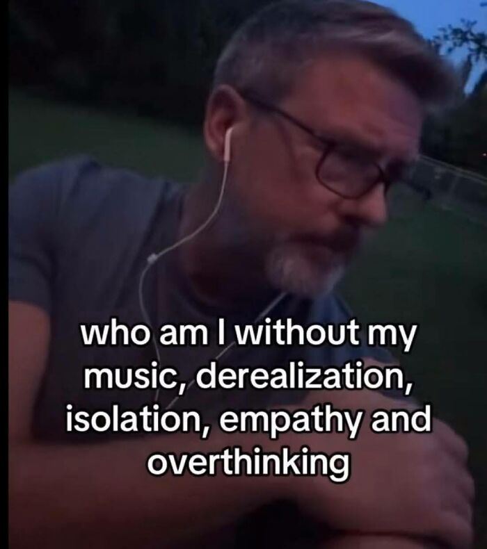 Man wearing glasses and earphones outdoors at dusk, reflecting on feelings related to neurodivergent experiences and thoughts.