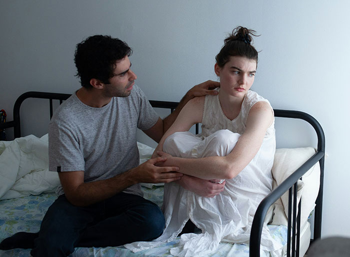 Couple having a tense conversation on bed, woman upset as boyfriend agrees to mow his ex's lawn and complains online. Couple having a tense conversation on bed, woman upset as boyfriend agrees to mow his ex's lawn and complains online.