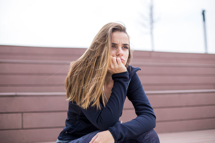 Bride looking upset and contemplative while sitting alone outdoors amid key wedding plans conflict with mom. Bride looking upset and contemplative while sitting alone outdoors amid key wedding plans conflict with mom.