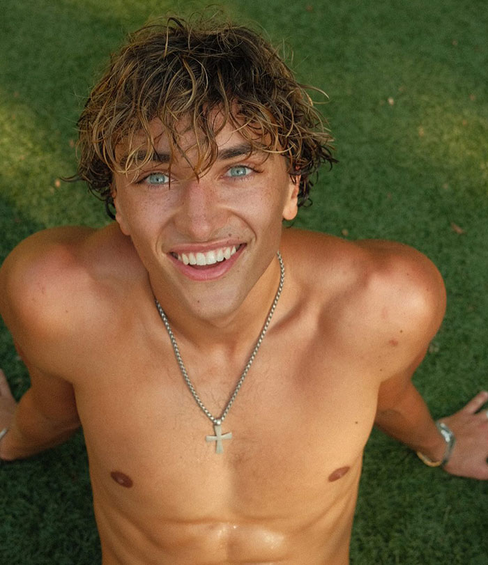 Young man with blue eyes and wet hair smiling shirtless on grass, highlighting genetics in a casual outdoor setting. Young man with blue eyes and wet hair smiling shirtless on grass, highlighting genetics in a casual outdoor setting.