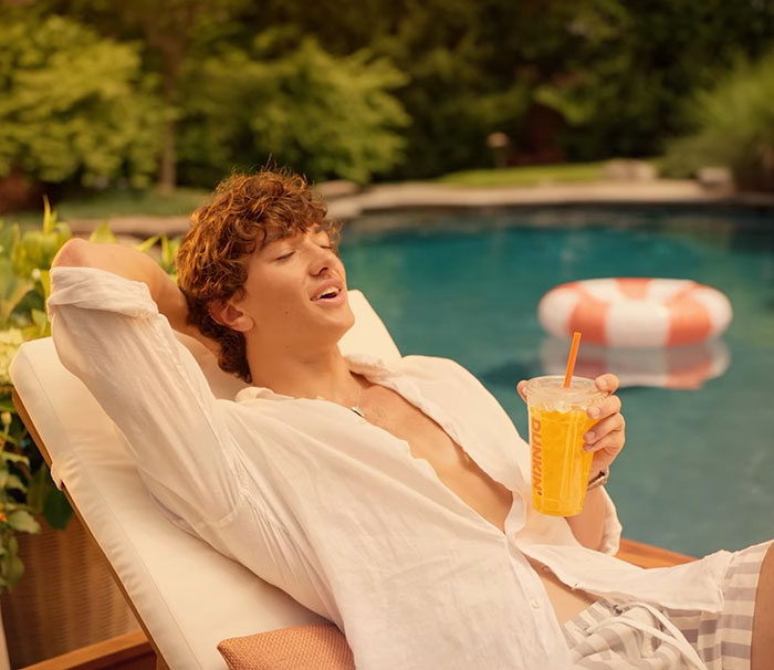 Young man relaxing by the pool holding a drink in a summer ad celebrating genetics and sparking woke outrage. Young man relaxing by the pool holding a drink in a summer ad celebrating genetics and sparking woke outrage.