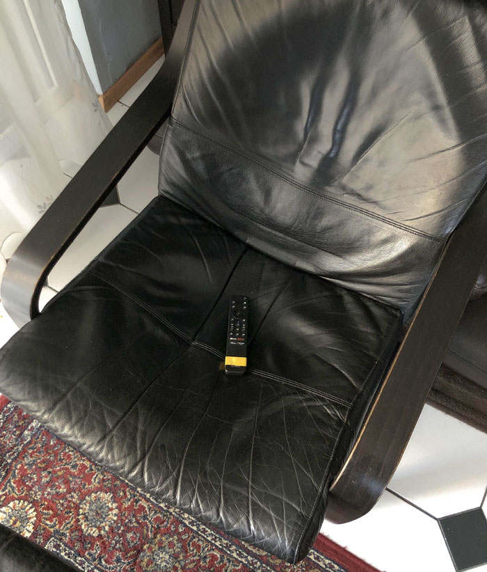Black leather chair with a TV remote placed on the seat demonstrating a genius life hack people actually use.