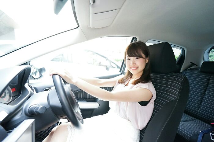 Young woman smiling inside a car, enjoying learning new things and discovering interesting facts.