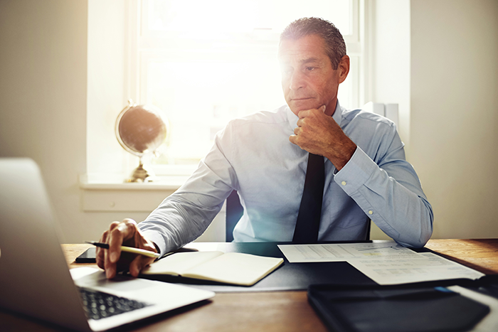 Man in office preparing to teach 12 years worth of knowledge before his PTO while working on laptop at desk.