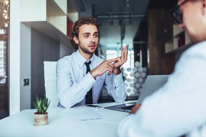 Young man in a blue shirt explaining job interview red flags indicating a potentially toxic workplace during a formal meeting.