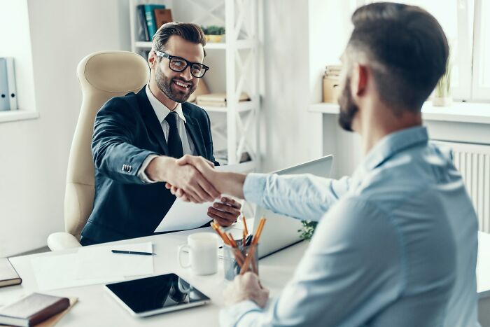 Two men shaking hands during a job interview, highlighting potential job interview red flags in a workplace setting.