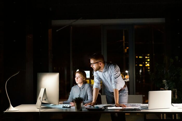 Two professionals working late at an office desk, highlighting job interview red flags in a toxic workplace environment.