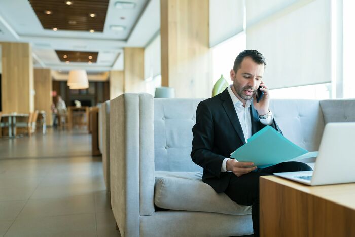 Businessman reviewing documents and talking on phone in a modern office, illustrating the smartest kids in their class grown up.
