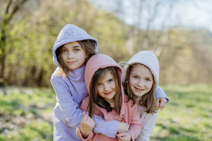 Three young girls wearing hoodies outdoors, representing people who actually experienced psychic predictions.