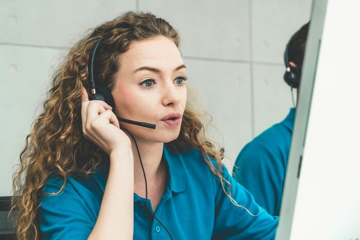 Customer service representative with headset focused on computer screen illustrating profession secrets concept.