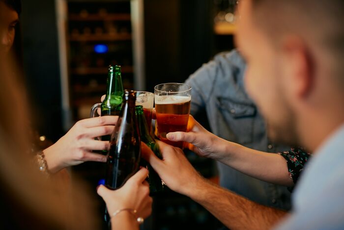Group of friends raising beer bottles and glasses in a toast, celebrating good news and positive moments together.
