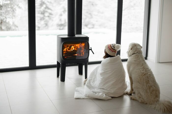 Child wrapped in a blanket by a fireplace with a dog, evoking creepy and terrifying experiences with imaginary friends.