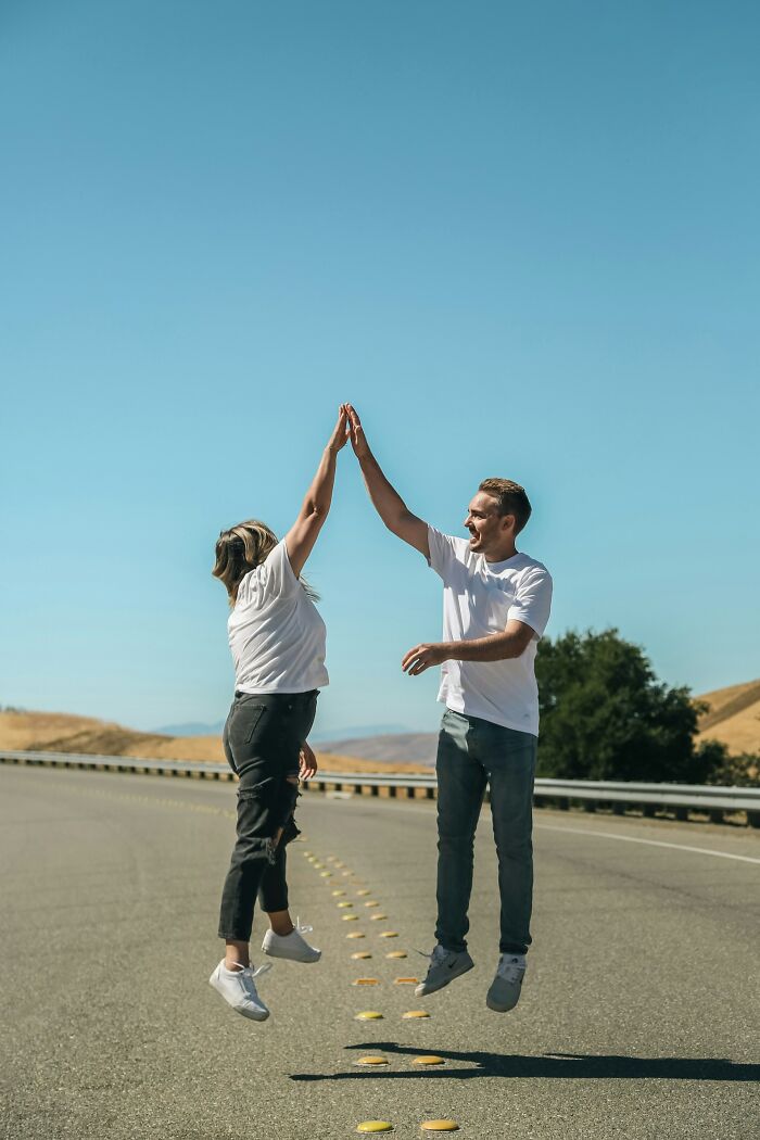 Two people jumping and high-fiving on an empty road under a clear blue sky, symbolizing Boops Boops fish facts.