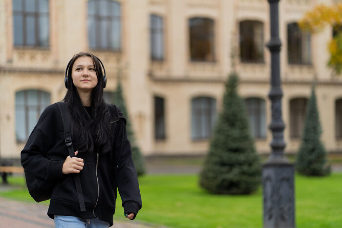 Young woman wearing headphones and a black hoodie walking outside, evoking mysterious and terrifying things people swear they’ve seen.