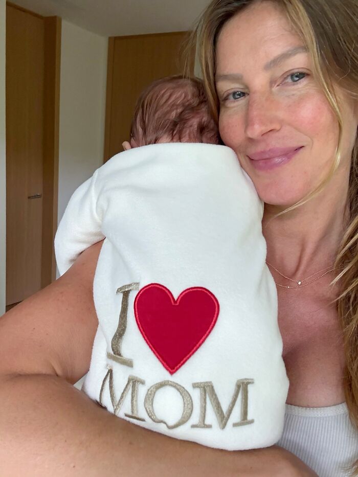 Gisele B&uuml;ndchen holding baby wearing I love mom outfit, highlighting tensions over parenting and Tom Brady&rsquo;s jab.
