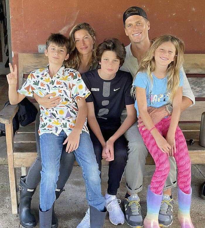 Gisele B&uuml;ndchen and Tom Brady sitting with their children on a bench, showing a family moment outdoors.