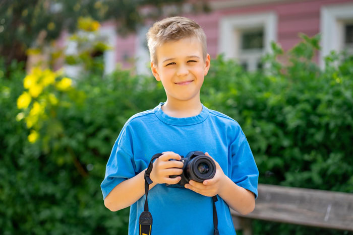 Smiling teen holding camera outdoors, representing teens picking up a portable darkroom at a surplus auction.