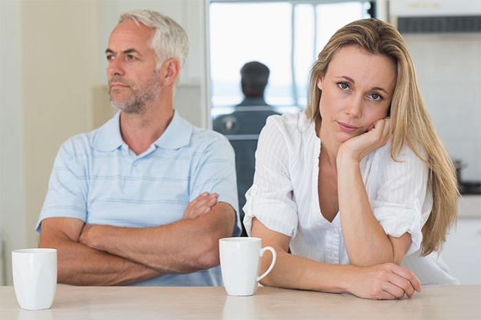 Woman feeling crushed and disappointed sitting with a man at a table, reflecting strained family emotions after graduation.
